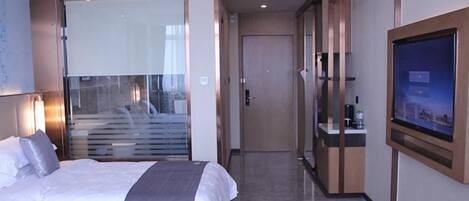 Habitación de hotel con cama, televisión y puerta de vidrio que da a un balcón.