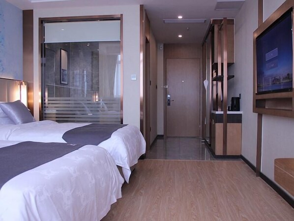 Habitación de hotel con dos camas, televisión y vista a una escalera.