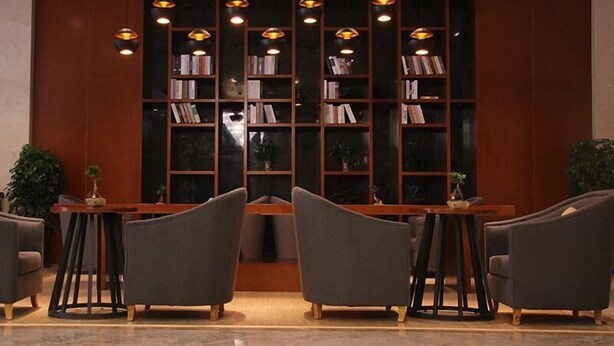 A modern library with bookshelves, pendant lights, and comfortable seating. - Greentree Eastern Liaocheng Linqing City Yandian Hotel (Liaocheng)