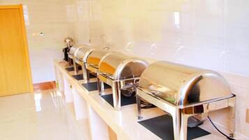 A row of buffet-style food dispensers in a clean, well-lit room with a tiled wall and a wooden door.