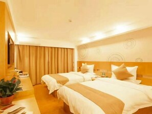 A hotel room with two beds, a wooden headboard, a small table with a plant, and a curtain.