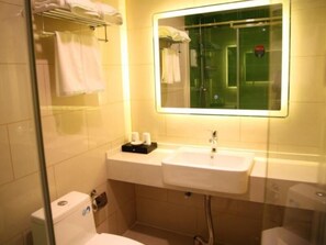 A bathroom with a white sink, a mirror, and a glass shower enclosure.