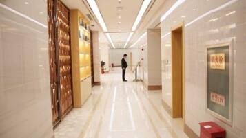 A hotel corridor with a polished floor, a reception area, and a person standing in the distance.