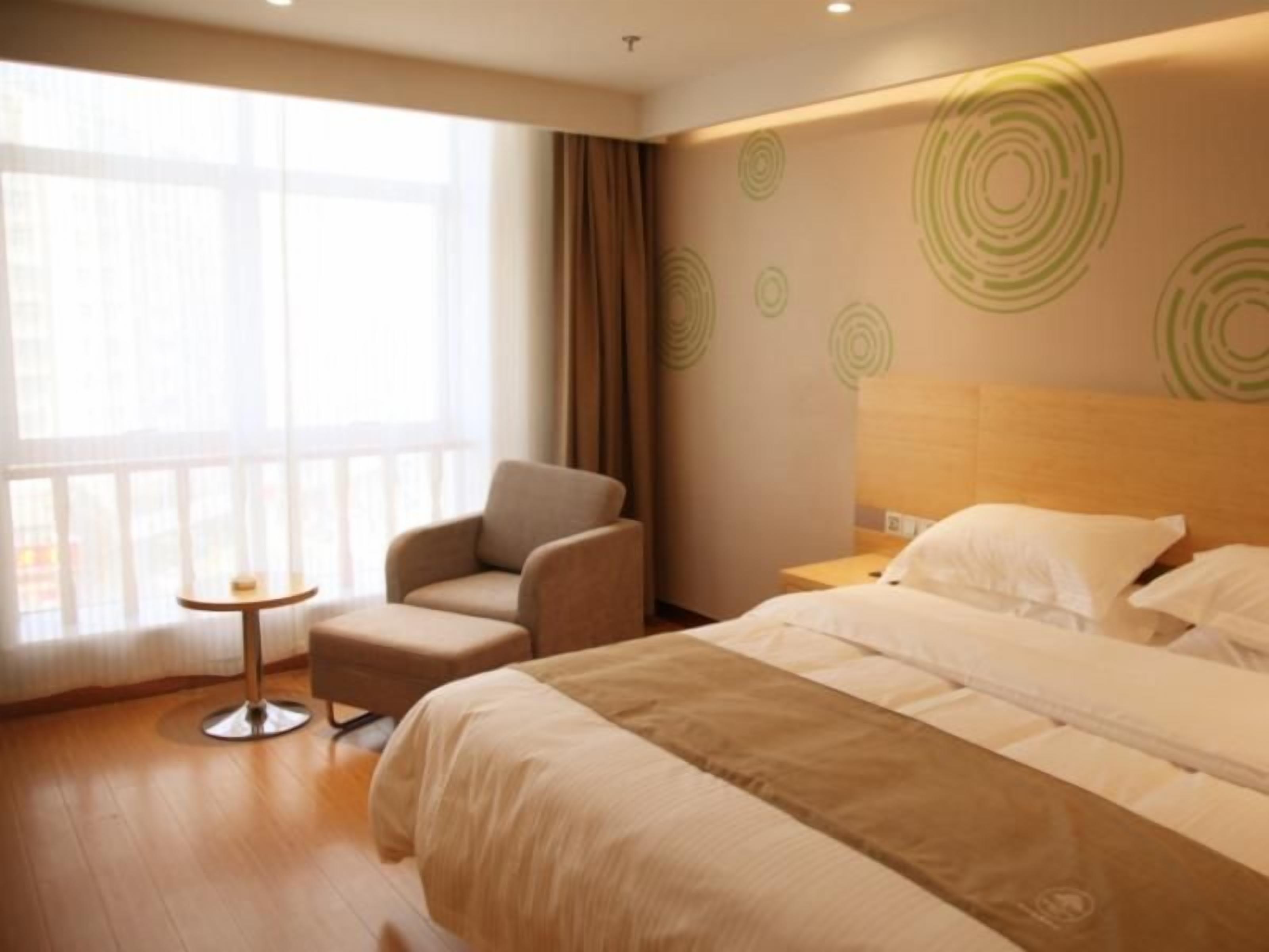 Una habitación de hotel con una cama, una silla, una mesita y un ventanal grande.