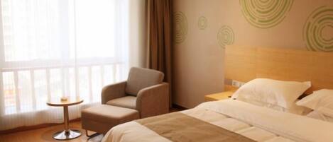 Una habitación de hotel con una cama, una silla, una mesita y un ventanal grande.