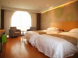 A hotel room with two beds, a desk, a chair, and a large window.