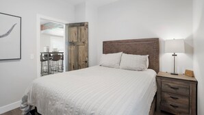 A bedroom with a large bed, a wooden headboard, a bedside table with a lamp, and a chair. - Newly Re-Finished 2 bed, 1 bath close to downtown (Sheridan)
