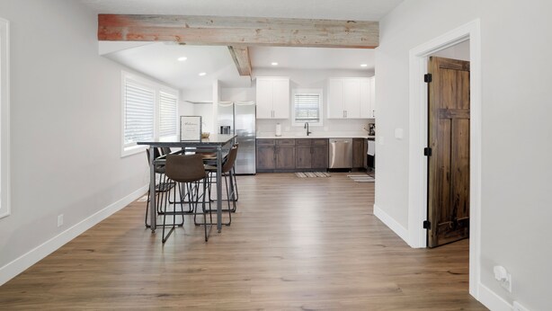 A modern kitchen with white cabinets, a wooden dining table, and a bar area. - Newly Re-Finished 2 bed, 1 bath close to downtown (Sheridan)