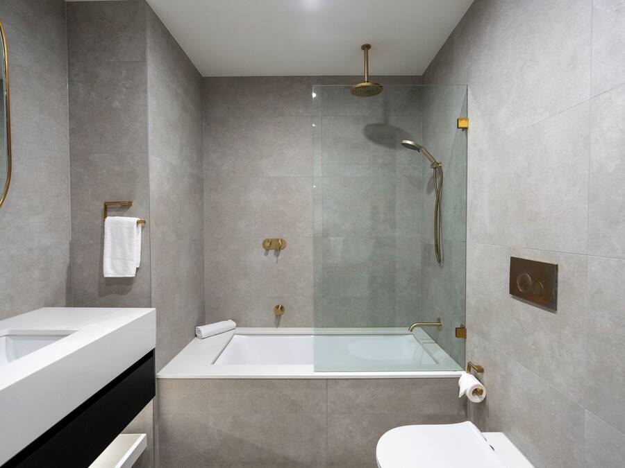 Een moderne badkamer met een glazen douchecabine, een wit bad en een apart toiletgedeelte.