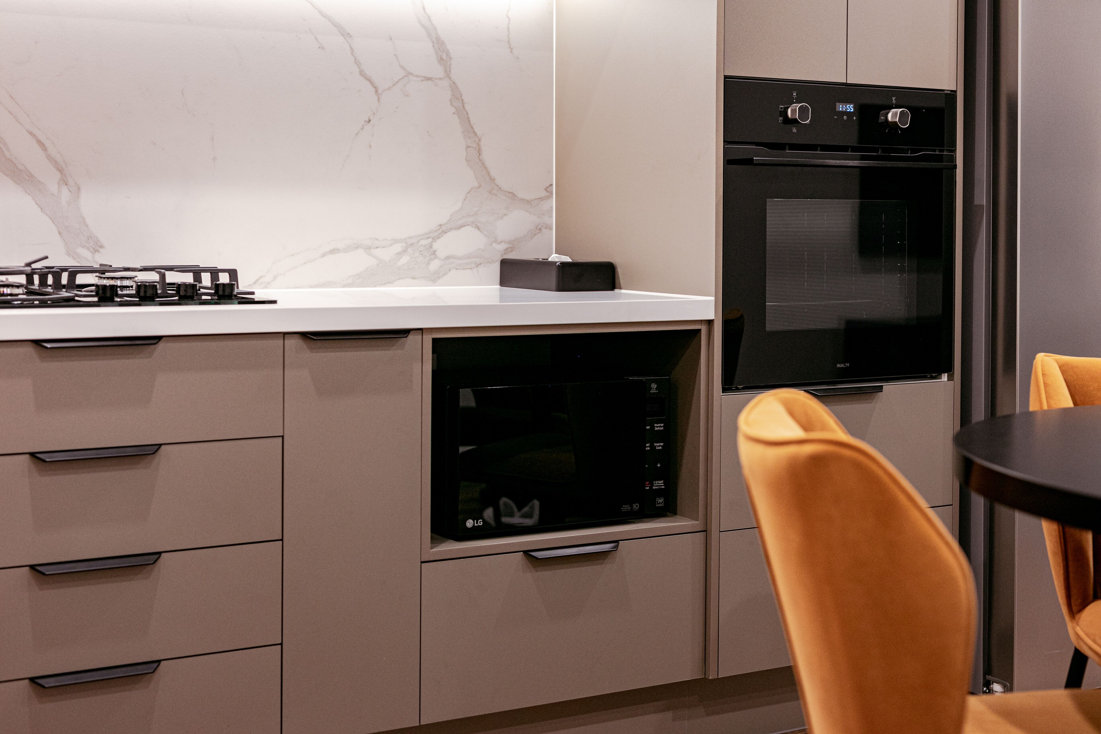 A modern kitchen with built-in appliances, including a microwave and oven, and a dining area with a table and chairs.