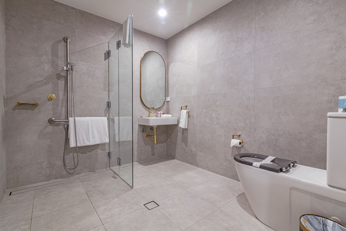 A modern bathroom with a glass-enclosed shower, a white sink, and a toilet.