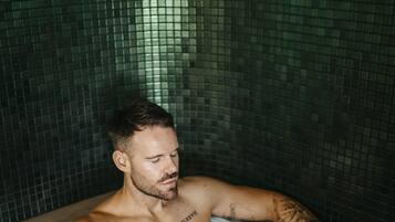 A man in a bathtub with tiled walls.