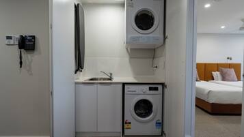 A compact laundry room with a washing machine, a sink, and a telephone.