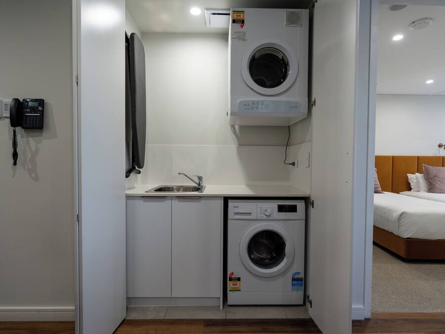 A compact laundry room with a washing machine, a sink, and a telephone.