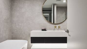 Un baño moderno con tocador blanco, espejo redondo y bañera.