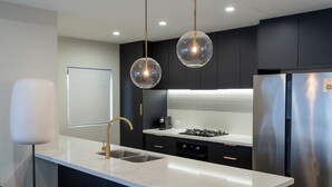 A modern kitchen with a white countertop, stainless steel appliances, and pendant lighting.