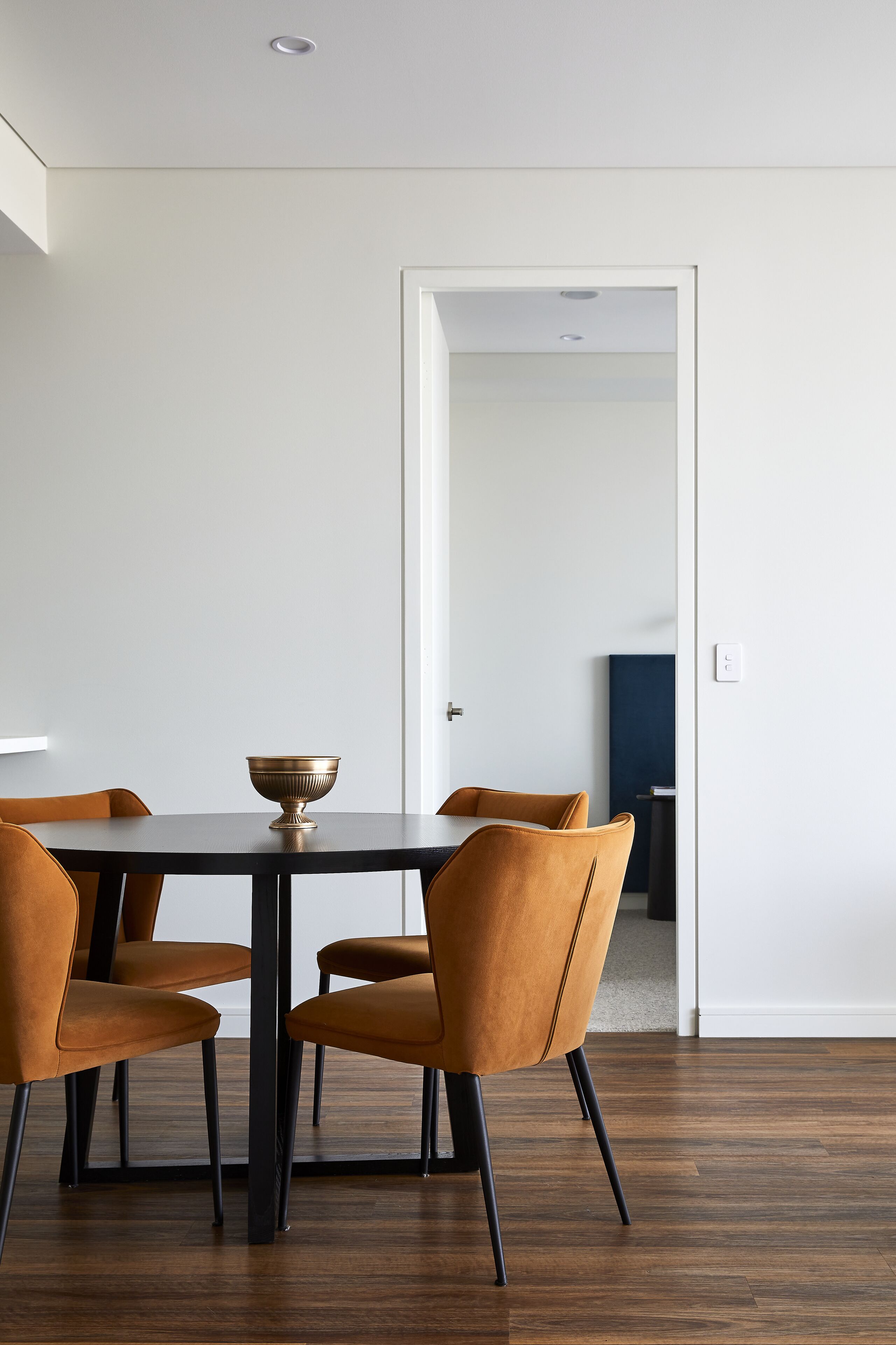 A dining area with a table and four chairs, a bowl on the table, and a door leading to another room.