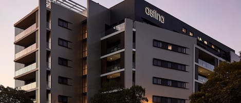 A modern hotel building with multiple floors, balconies, and a prominent 'astina' sign.