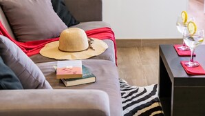 A modern living room with a grey sofa, a red throw blanket, a straw hat, and a small table with two glasses of water and lemon slices. - Rosamar 313 Luxury sea view wifi (Arona)