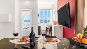 A modern living room with a dining area, a large flat-screen TV mounted on the wall, and a view of the sea through the windows. - Rosamar 313 Luxury sea view wifi (Arona)