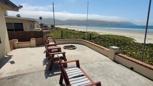 A patio with wooden lounge chairs and a view of the beach and mountains. - CASA MARBELLA 2BR/1BA Private Beach-Front Home (Ensenada)