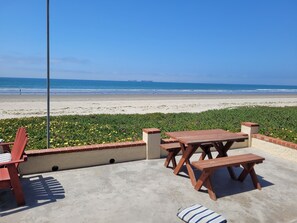 Une terrasse avec des meubles en bois donnant sur une plage.