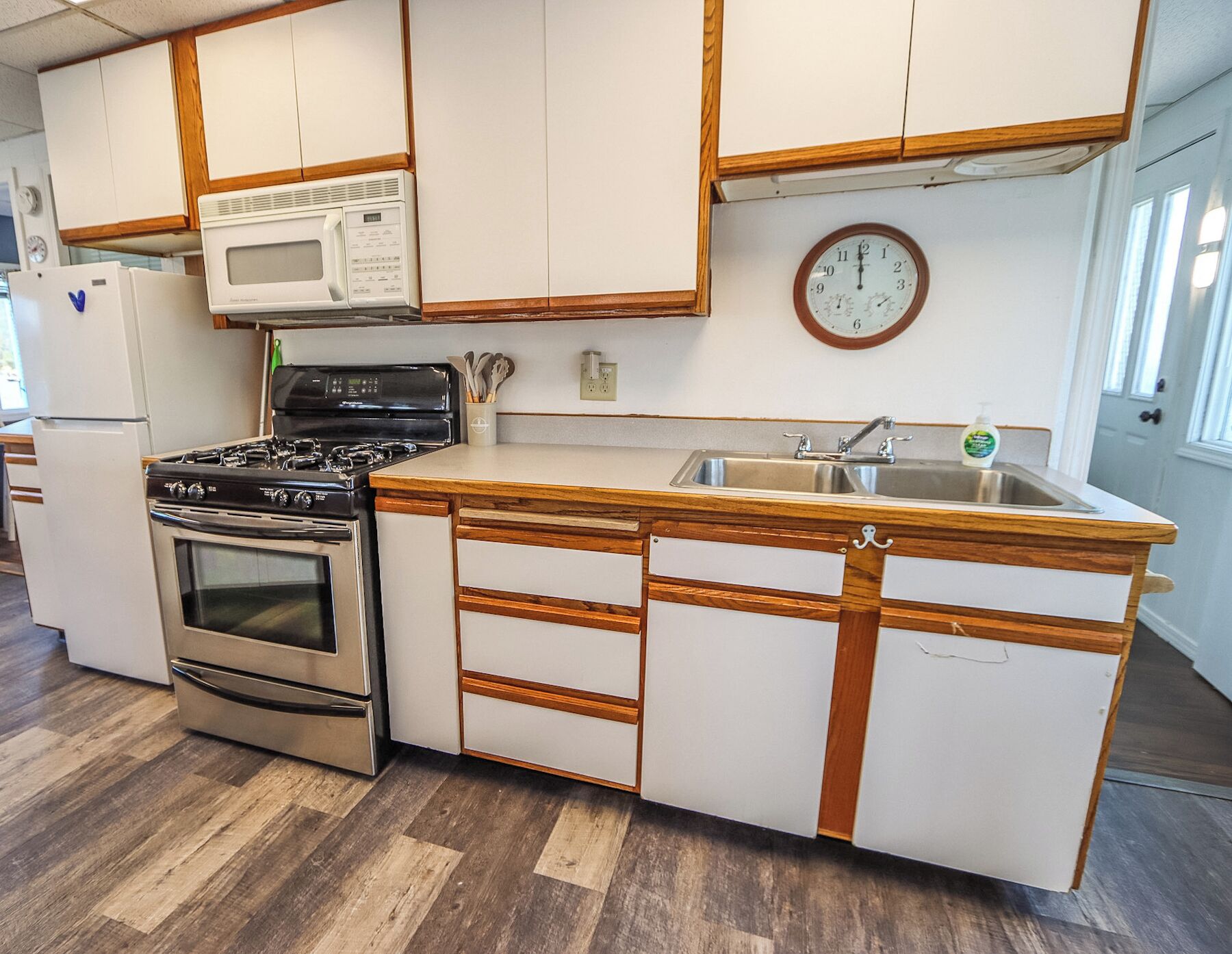 A kitchen with white cabinets, a stainless steel stove, a microwave, and a wooden countertop.