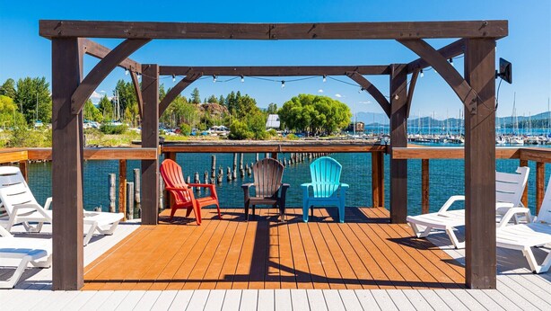Terraza de madera con sillones de descanso y un pabellón con vistas a un puerto deportivo.