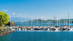Un puerto deportivo con barcos amarrados, un edificio de madera y montañas al fondo.