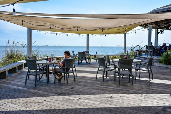 Un patio al aire libre con mesas y sillas, con vista a un cuerpo de agua.