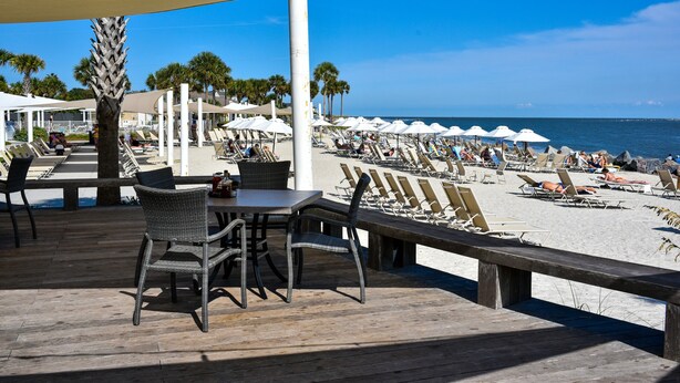 A beachside patio with outdoor seating and a view of the beach.