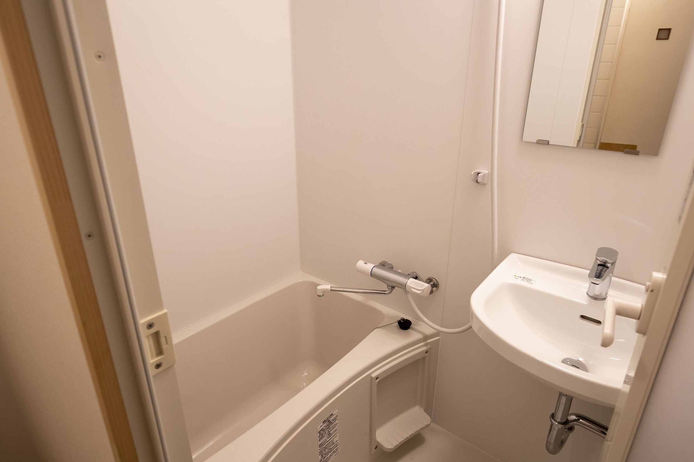 A bathroom with a white bathtub, a white sink, and a mirror above the sink.