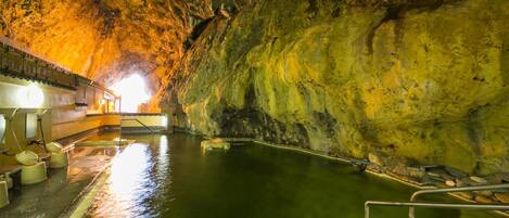 A cave with a swimming pool, benches, and a viewing platform.