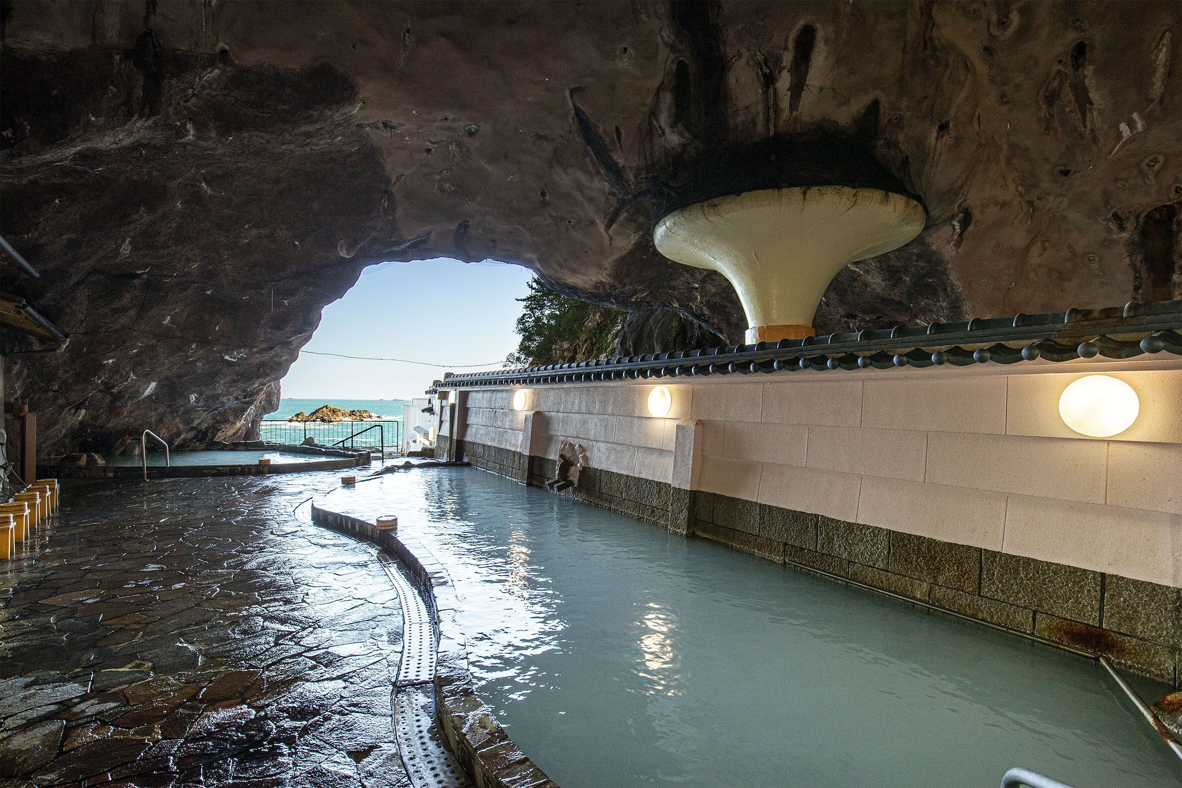 A natural pool with a stone floor and a large rock formation overhead.