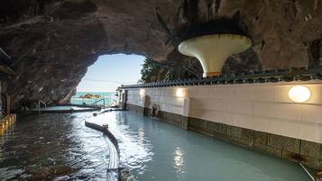 A natural pool with a stone floor and a large rock formation overhead.