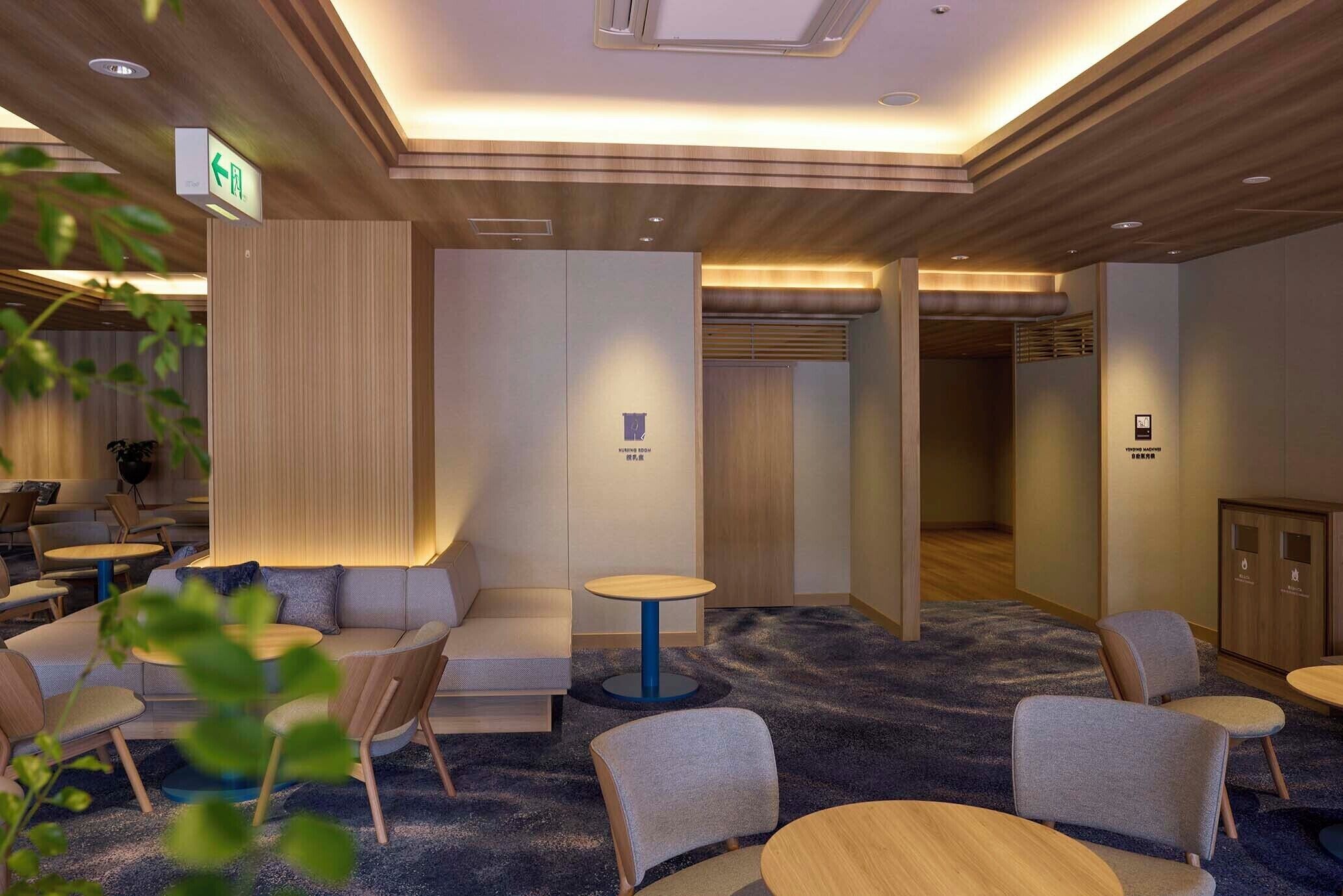 A hotel lobby with seating areas, a reception desk, and a clear exit sign.