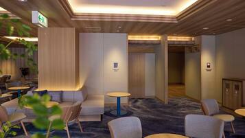 A hotel lobby with seating areas, a reception desk, and a clear exit sign.