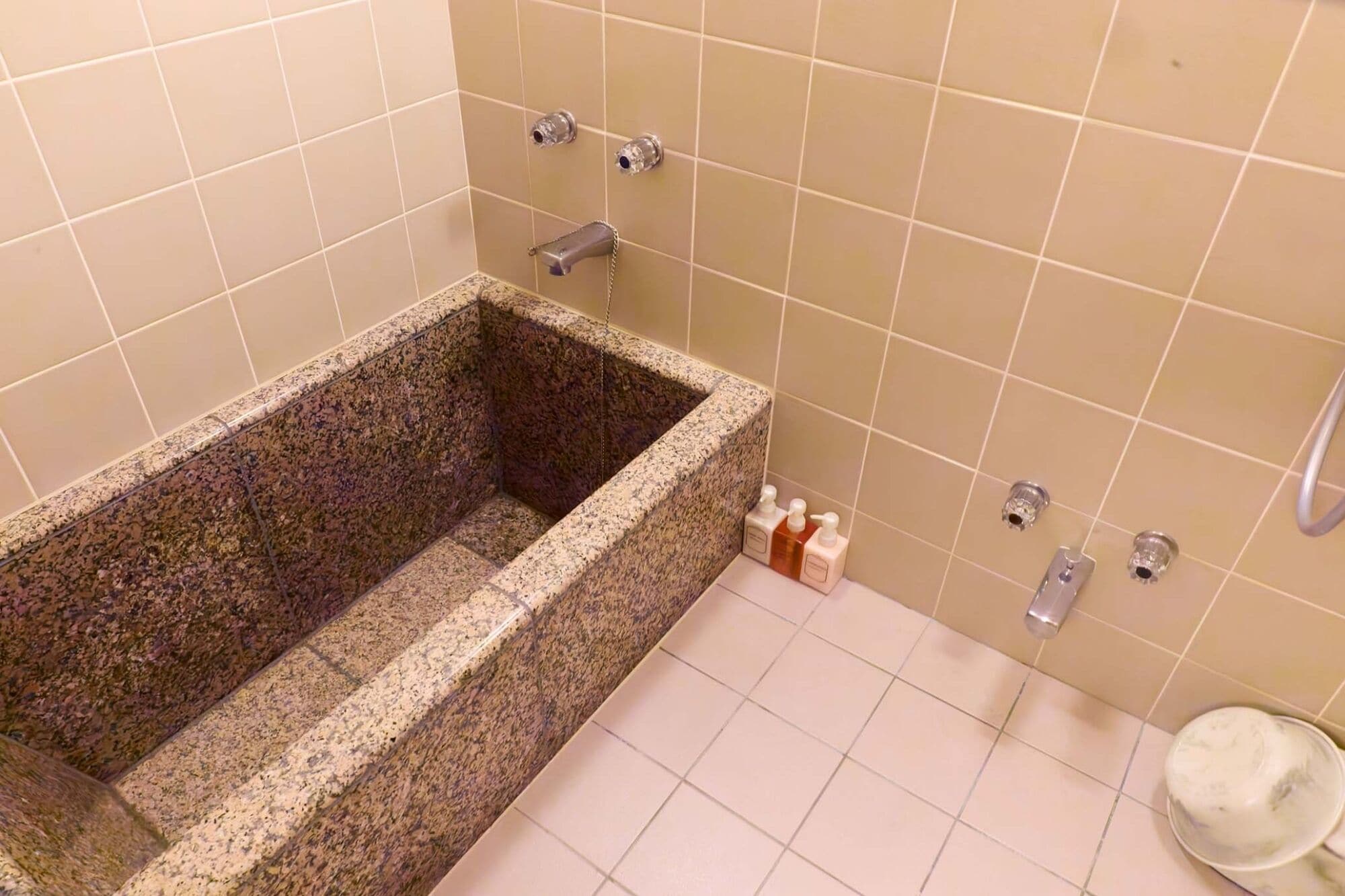 Un baño con una bañera de granito rectangular, un inodoro y un lavamanos con grifo.