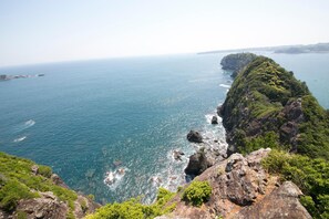 A coastal landscape with rocky cliffs and a clear view of the sea.