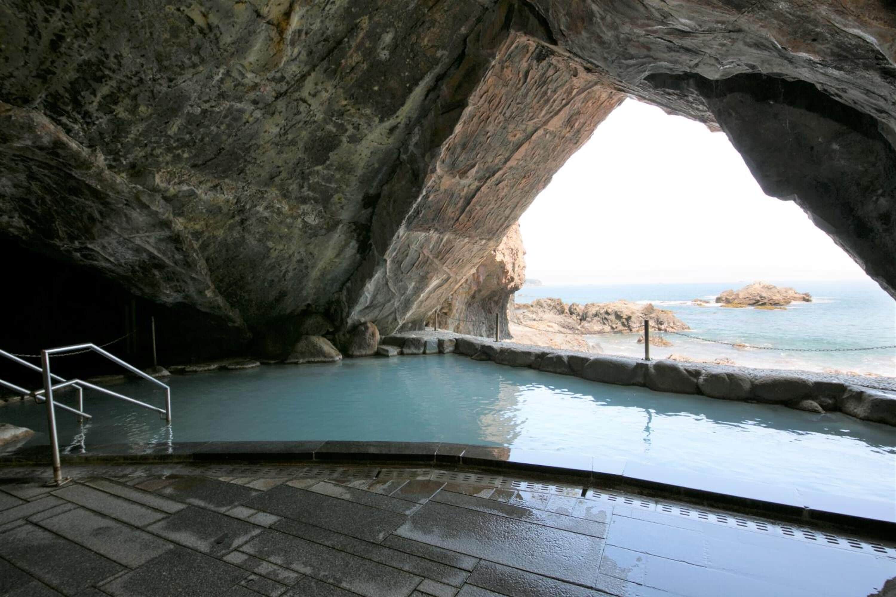 A natural rock formation with a pool and steps leading to a beach.