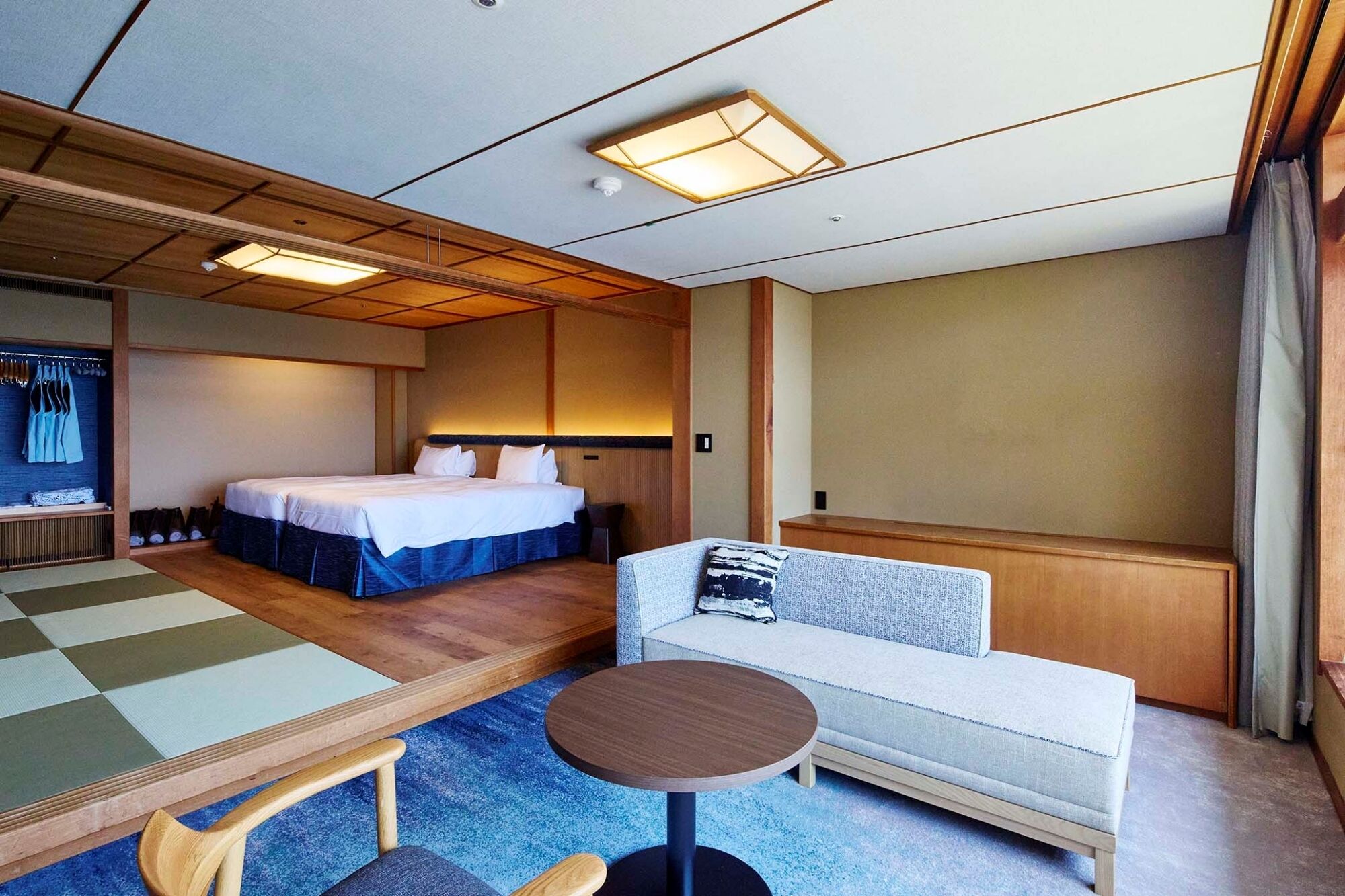 Een hotelkamer met een bed, een sofa, een kleine tafel en een traditioneel Japans tatami-matgedeelte.