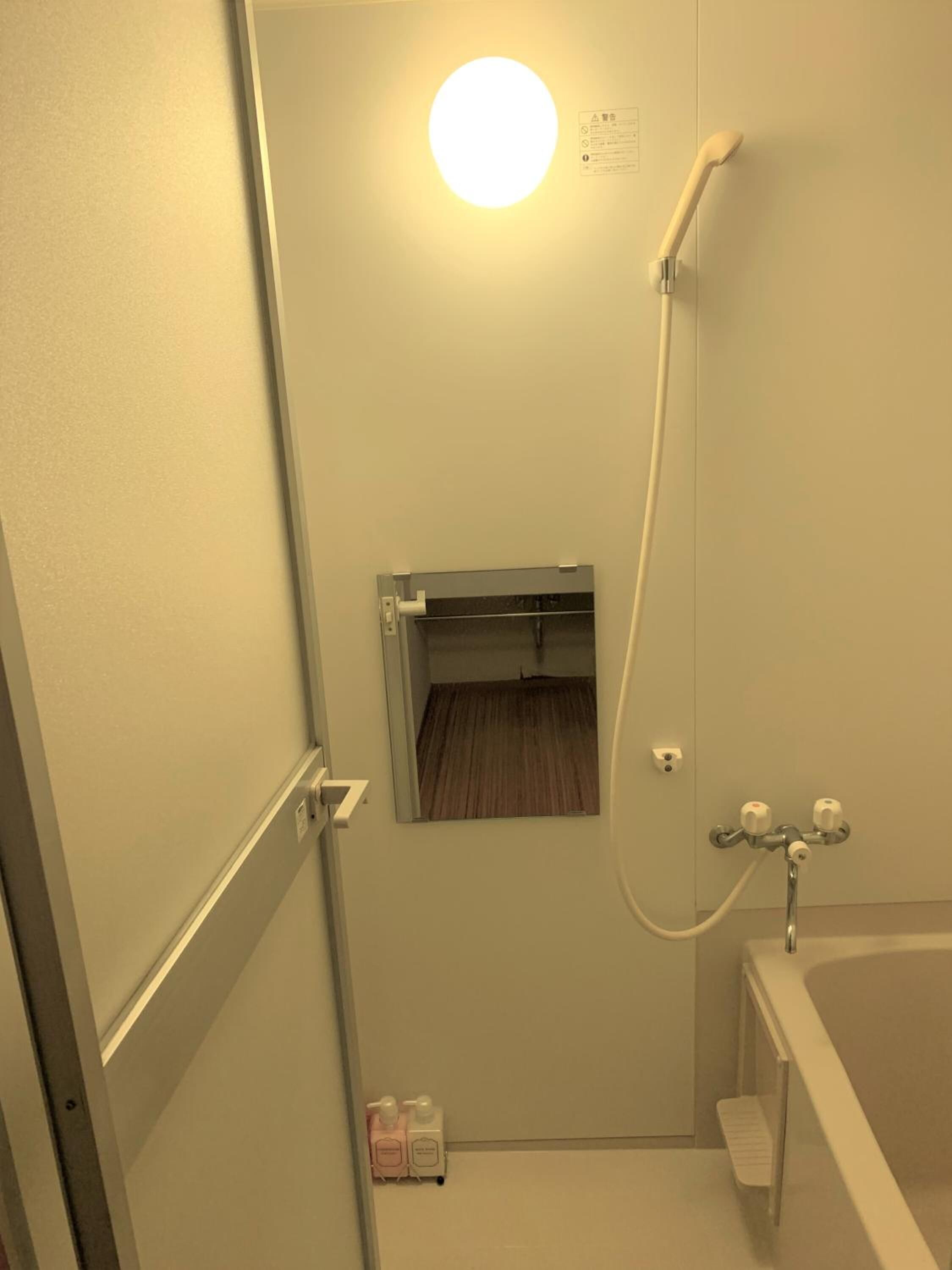 Een kleine, smalle badkamer met een douche, toilet en spiegel.