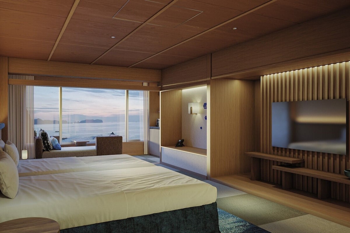 Une chambre d’hôtel moderne dotée d’un grand lit, d’une télévision, d’un bureau et offrant une vue sur la mer.