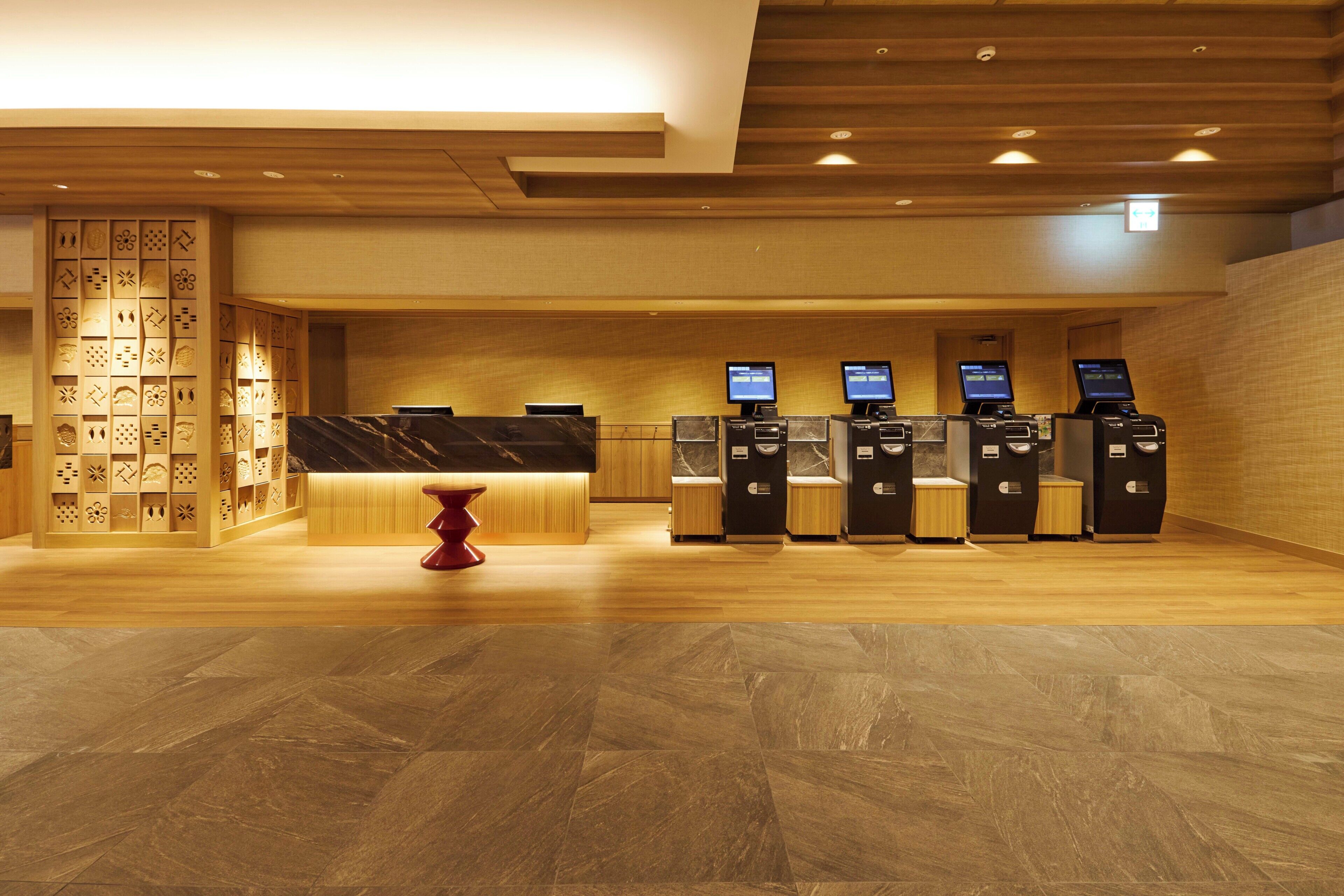 A reception area with a marble counter, a red stool, and multiple self-service kiosks.