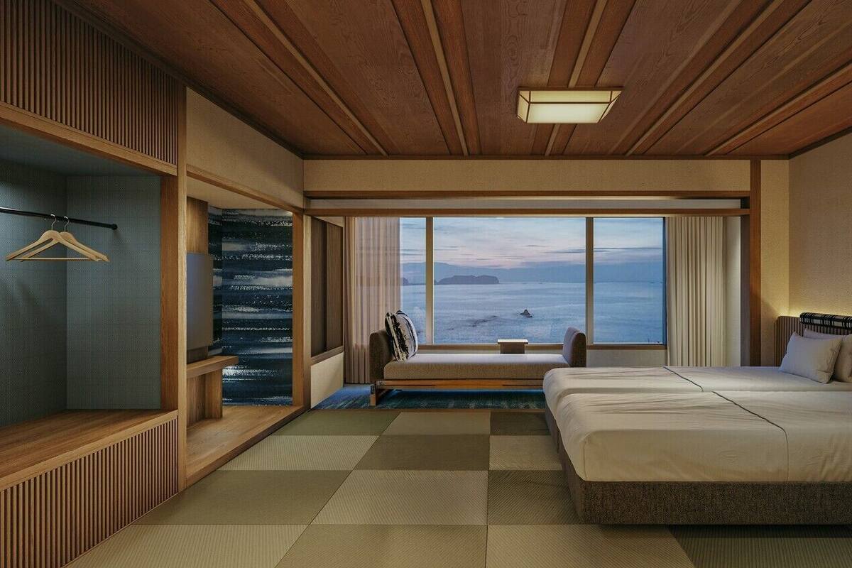 Une chambre d’hôtel dotée d’une grande fenêtre, d’un lit, d’un coin salon et d’une armoire.