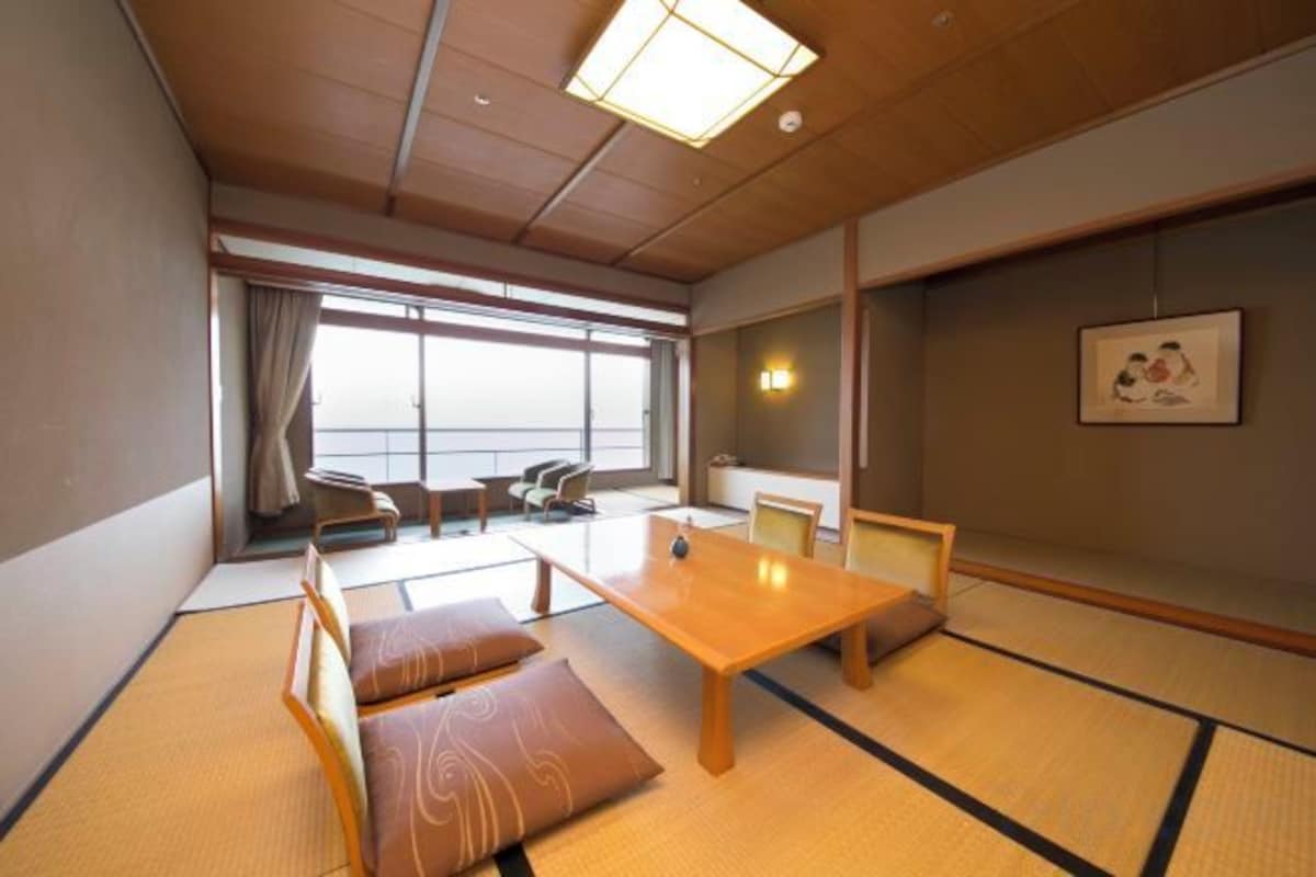 A traditional Japanese room with tatami flooring, a low table, and a sofa.