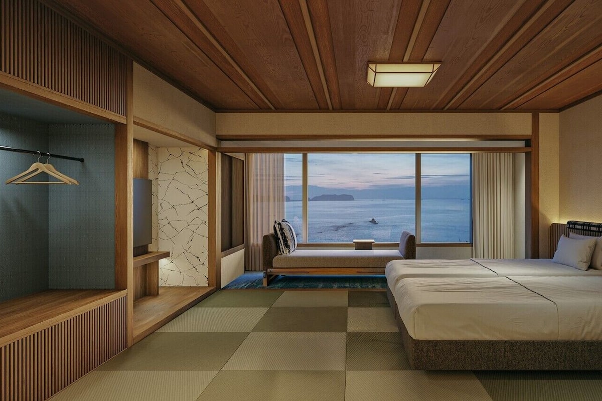 Une chambre d’hôtel avec un grand lit, un coin salon, une télévision et une vue sur la mer.