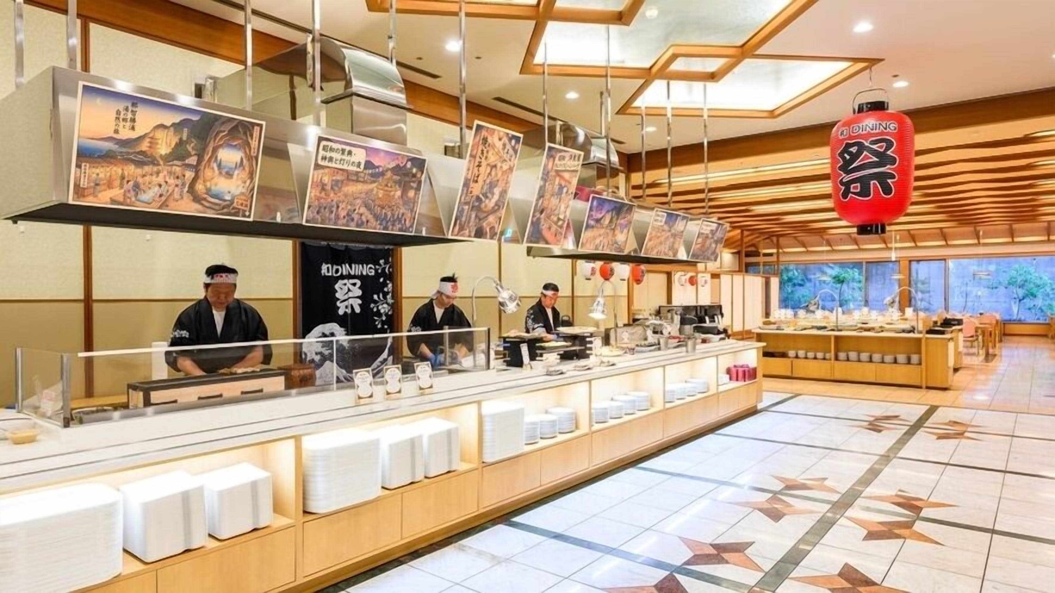 Interno di un ristorante sushi con bancone, personale e bacheche con il menù.