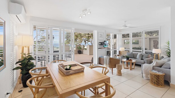 A spacious living area with a wooden dining table, comfortable seating, and a sofa.
