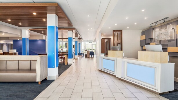 Un hall d’hôtel moderne avec un comptoir d’accueil, un espace salon et une vue sur l’intérieur.